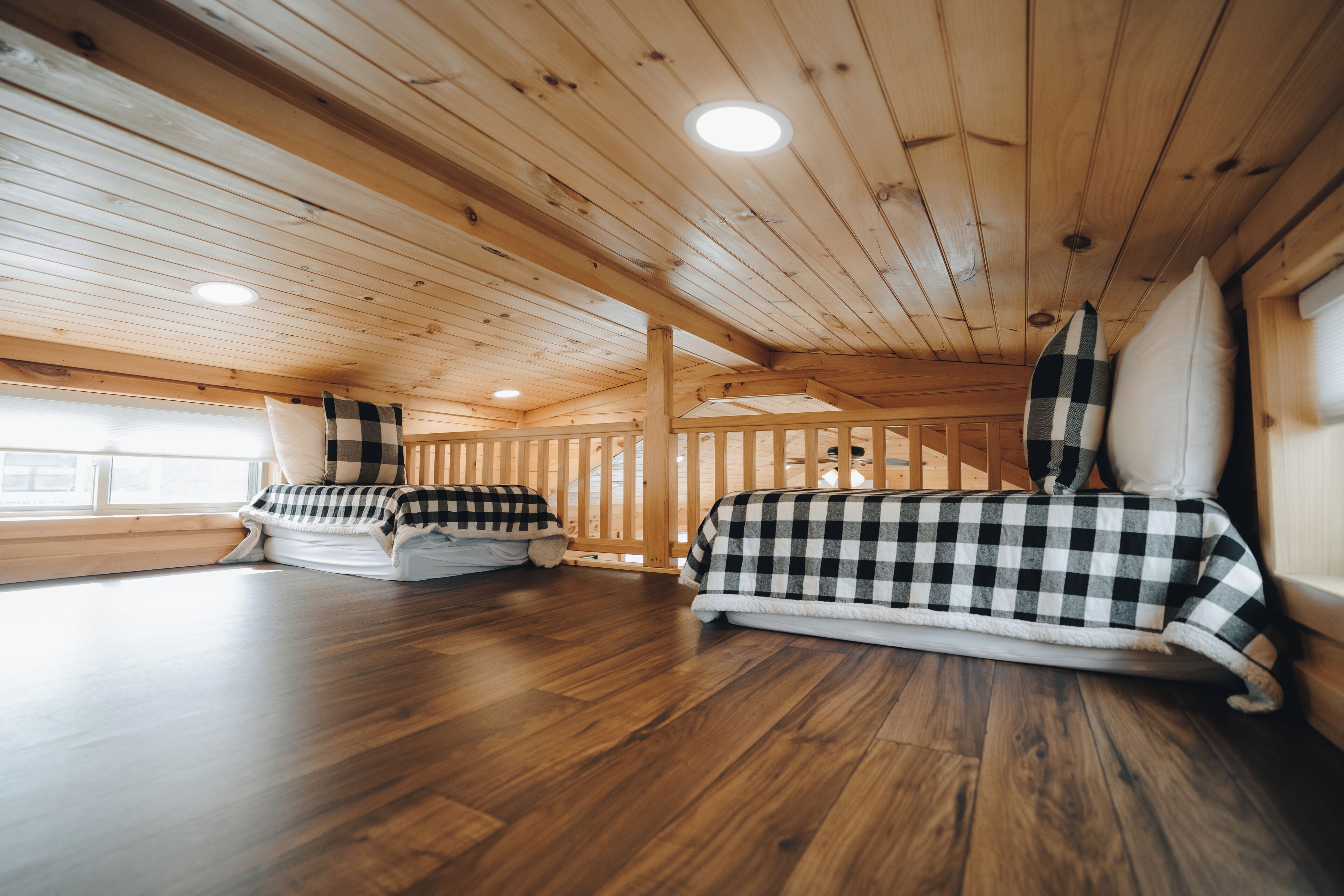 Eine Hütte mit Holzdielen und schräg stehender Decke. Es gibt zwei Betten mit karierten Bettbezügen.