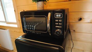 A black microwave oven with a digital display on a wooden table.