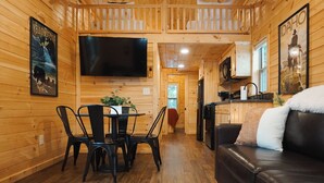 A cozy cabin interior with a dining area, a living room with a leather couch, and a kitchen area. - Blue Buffalo Resort (Island Park)