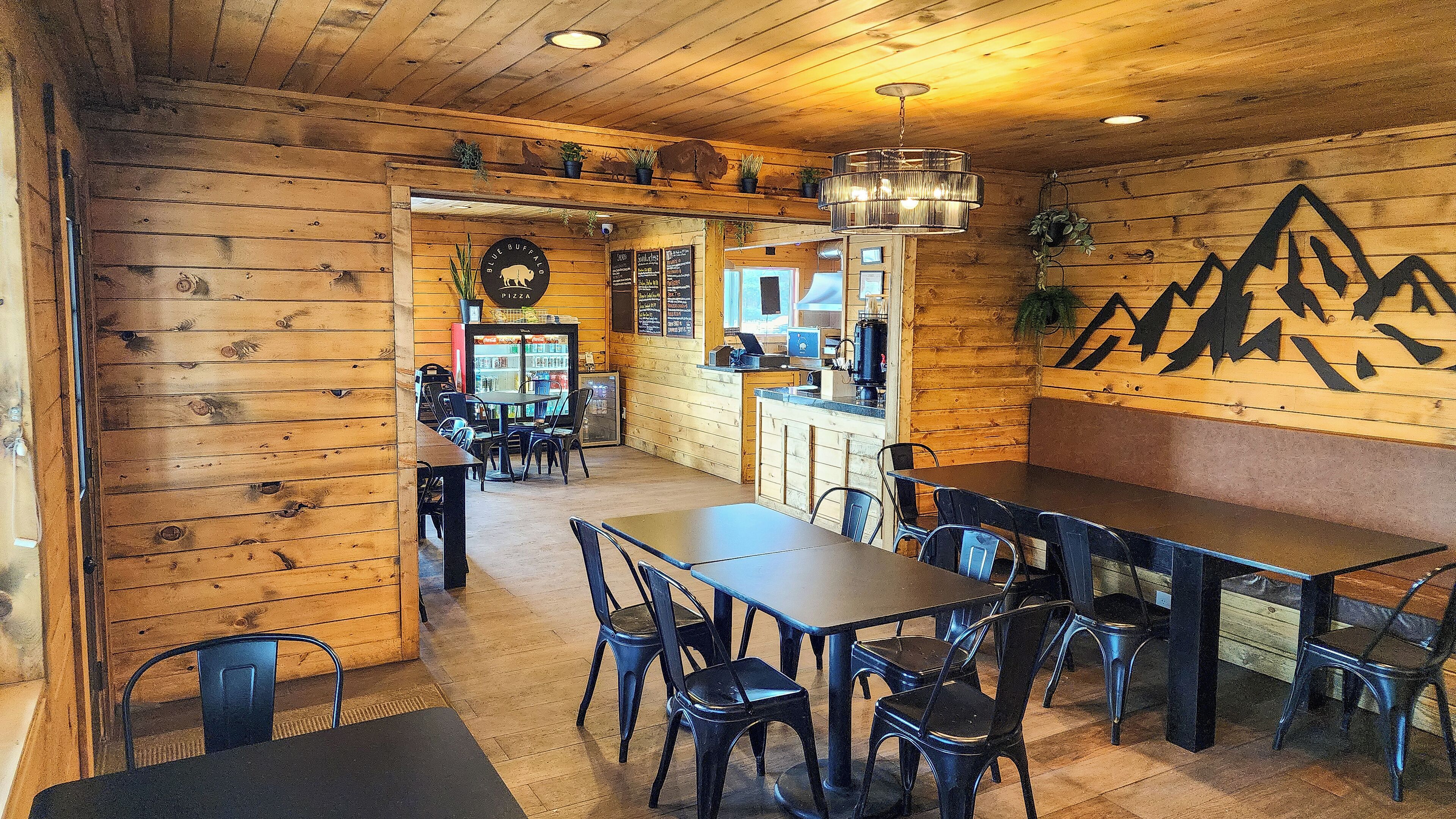 Ein rustikales Holzinterieur mit einem Essbereich, der Tische, Stühle, einen Kühlschrank und eine Speisekarte beinhaltet.