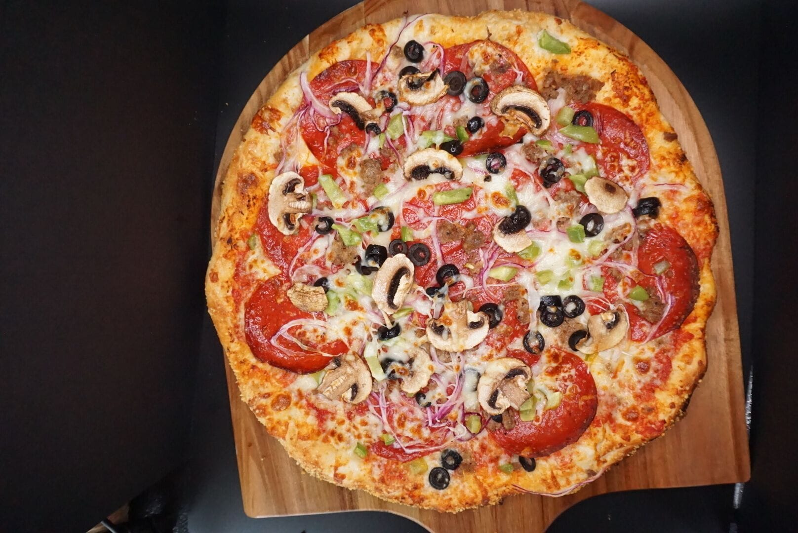 A pizza with various toppings on a wooden board.