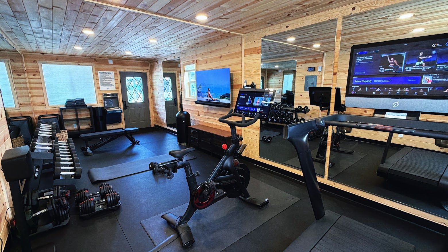 A gym with exercise equipment, a television, and a mirrored wall.