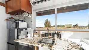 A compact kitchen with a sink, microwave, and refrigerator. - Blue Moon Tiny House | Hot Tub · Sauna · Olympic Views (Port Angeles)