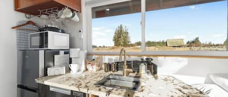 A compact kitchen with a sink, microwave, and refrigerator.