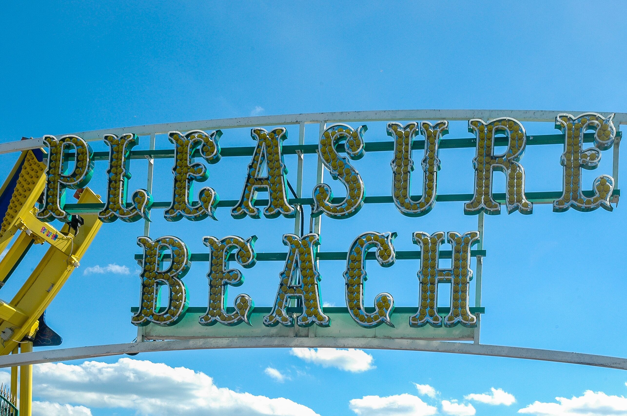 A sign with the words "PLEASURE BEACH" in large, decorative letters.