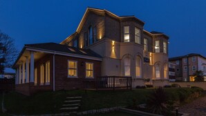 Una casa grande de varios pisos con un porche delantero llamativo y un césped bien cuidado.