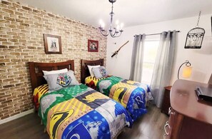 A room with two beds, a brick wall, a chandelier, a birdcage, and a window with curtains. - Getaway for SALE 3BR Villa w/Pool&BBQ Themed Rooms near Disney (Kissimmee)
