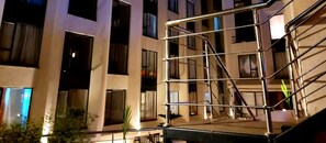 Un immeuble à plusieurs étages, avec une structure d’échafaudage métallique en premier plan.