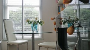 A dining area with two white chairs, a glass table, and a vase with flowers. - Chic Flat in Kentish Town, 5min to Hampstead Heath (London)