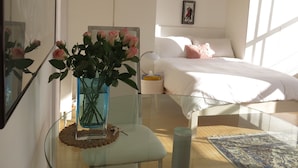 A bedroom with a bed, a bedside table with a vase of flowers, a bedside lamp, and a framed picture on the wall. - Chic Flat in Kentish Town, 5min to Hampstead Heath (London)