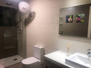 Une salle de bain moderne avec une douche à parois de verre, des toilettes et un lavabo avec un miroir au-dessus.