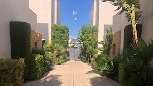 A pathway leading to a building with a stone wall and greenery on either side. - Stunning villa, large private pool, 8' from beautiful beach (Quesada)