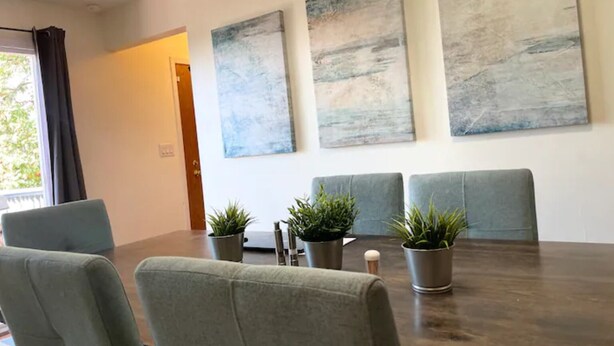 A conference room with a dark wooden table, four grey chairs, and three potted plants. - Dog 🐾 friendly home with a view 🌅 near airport ✈️ (Des Moines)