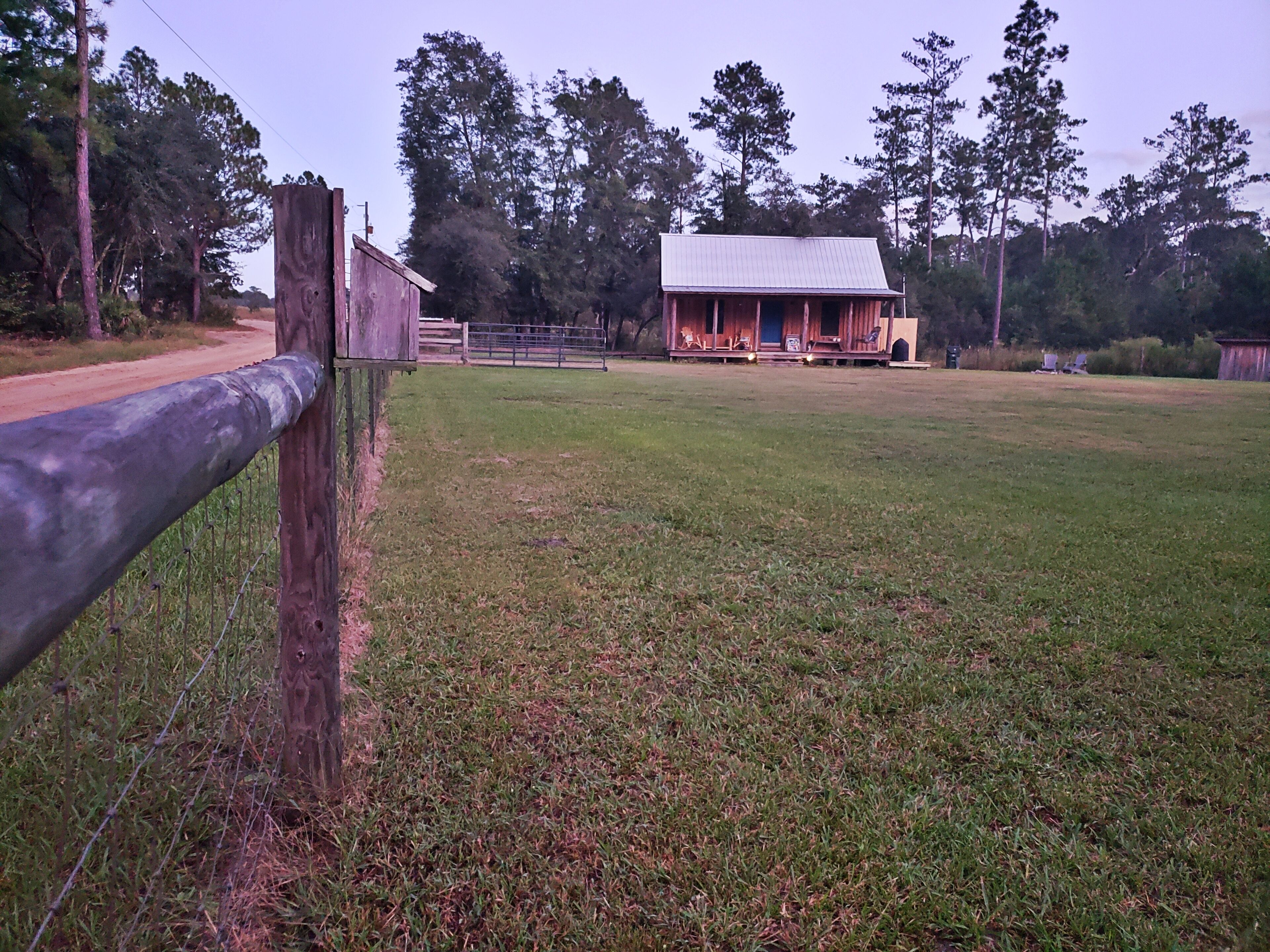 A fenced property with a building that has a porch and a covered area.