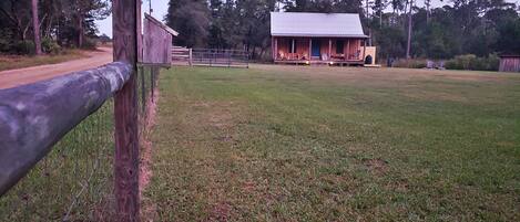 A fenced property with a building that has a porch and a covered area.