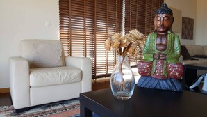A room with a sofa, a Buddha statue, and a vase with dried flowers. - Holiday Apartment in Madeira (Caniço)