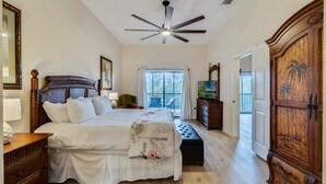A bedroom with a large bed, a ceiling fan, a wooden wardrobe, and a television. - Caribe Cove -Gorgeous and Cozy   Close to Disney (Kissimmee)