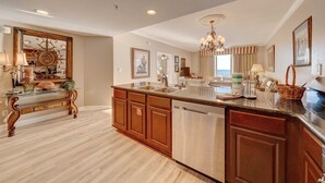A spacious kitchen with wooden cabinets, a stainless steel dishwasher, and a large island with a sink.