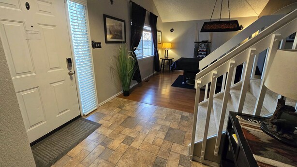 A spacious hallway with a wooden floor, a white door, and a staircase leading to an upper level. - Cozy Colorado home with Serene views meant for pure relaxation! (Henderson)