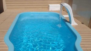 Ein rechteckiger Pool mit klarem, blauem Wasser, umgeben von einer Holzterrasse.