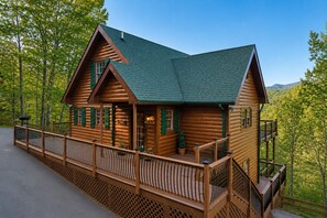 A log cabin with a balcony, a porch, and a view of the surrounding forest. - Summer Sale!-Views-Hot Tub-Pool Table-Movie Room (Pigeon Forge)