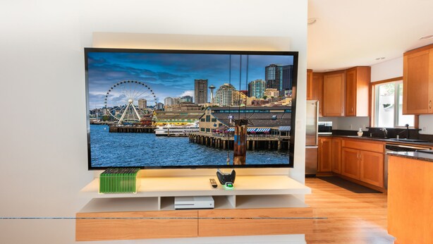Una cocina moderna con armarios de madera, un televisor integrado mostrando un paisaje urbano y piso de madera.