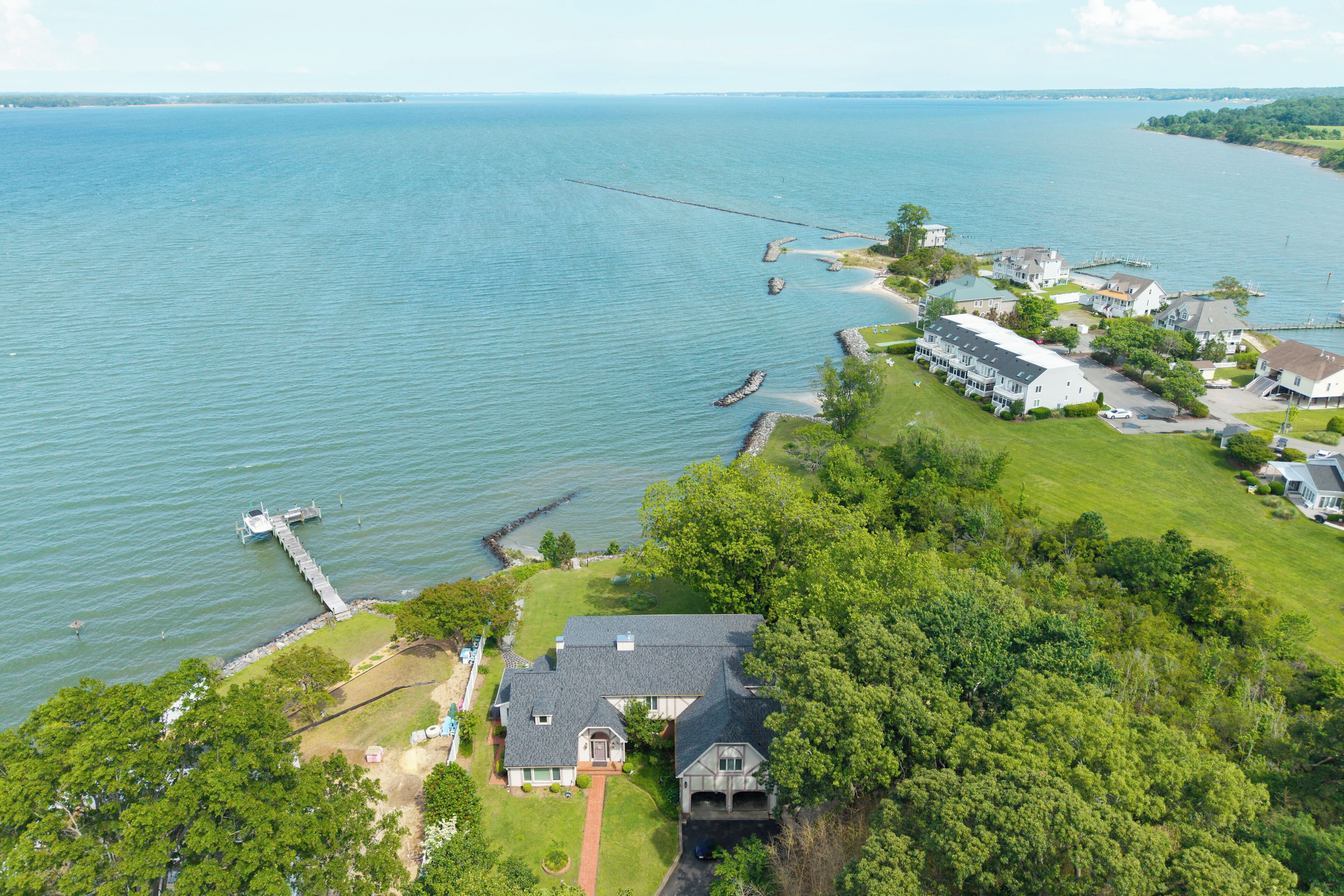 An aerial view of a lakeside property with multiple houses, a dock, and a pier extending into the water.