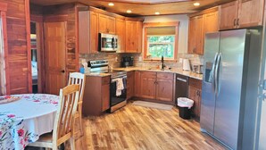 A compact kitchen with wooden cabinets, a stainless steel refrigerator, and a microwave. - 2-bedroom vacation home near Mark Twain National Forest (Potosi)