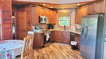 Una cocina compacta con armarios de madera, un refrigerador de acero inoxidable y un microondas.