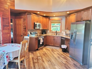 A compact kitchen with wooden cabinets, a stainless steel refrigerator, and a microwave.