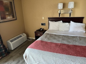 Cozy retreat with a neatly made bed, wall-mounted nightstand, and a painting above.