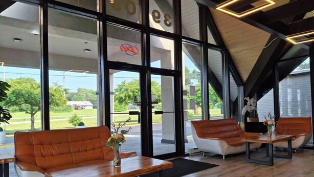 A modern interior with leather seating, large windows, and a view of the outdoors. - Hotel Weston RFD (Rockford)