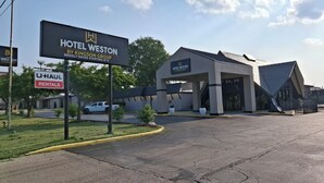 A hotel entrance with a sign for Hotel Weston by Kingdon Group, a U-Haul rental sign, and a parking lot. - Hotel Weston RFD (Rockford)