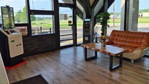 An indoor seating area with a wooden table, a leather couch, and a potted plant. - Hotel Weston RFD (Rockford)