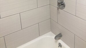 A bathroom with a bathtub, a showerhead, and a towel rack. - Hotel Weston RFD (Rockford)