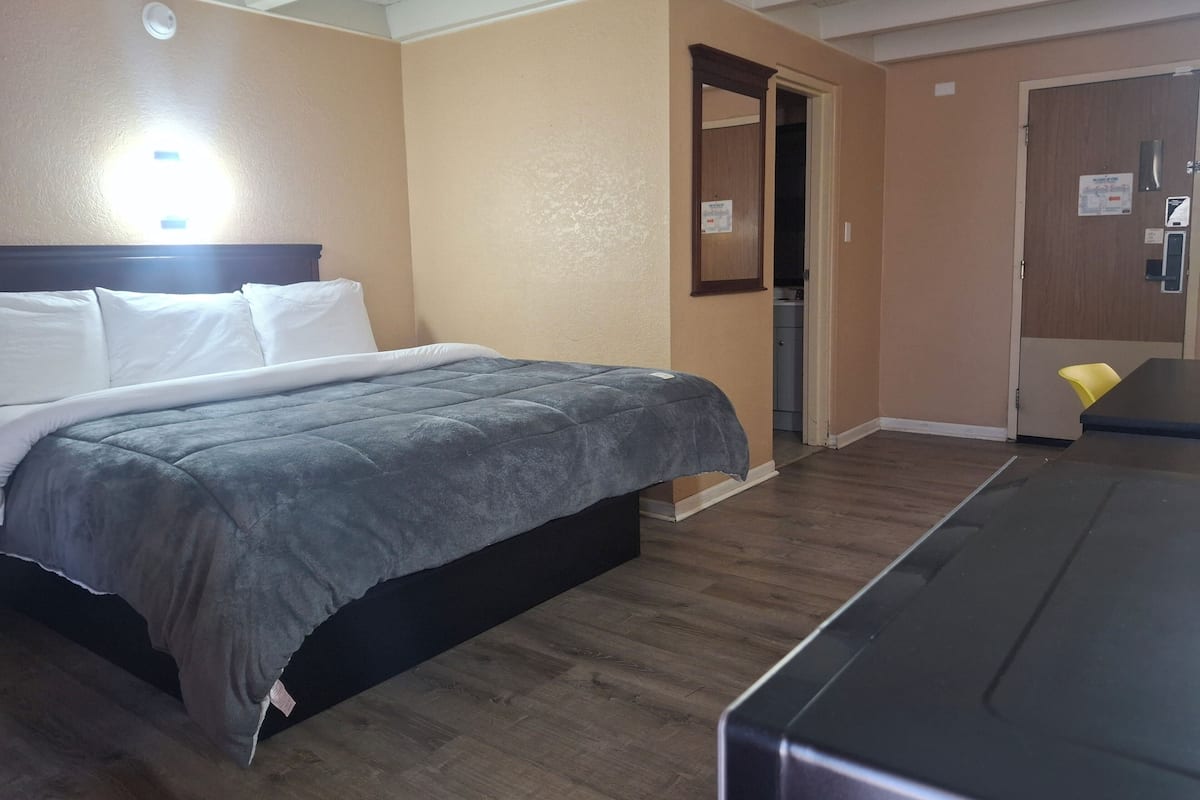 A hotel room with a bed, a desk, a chair, and a door leading to a bathroom.