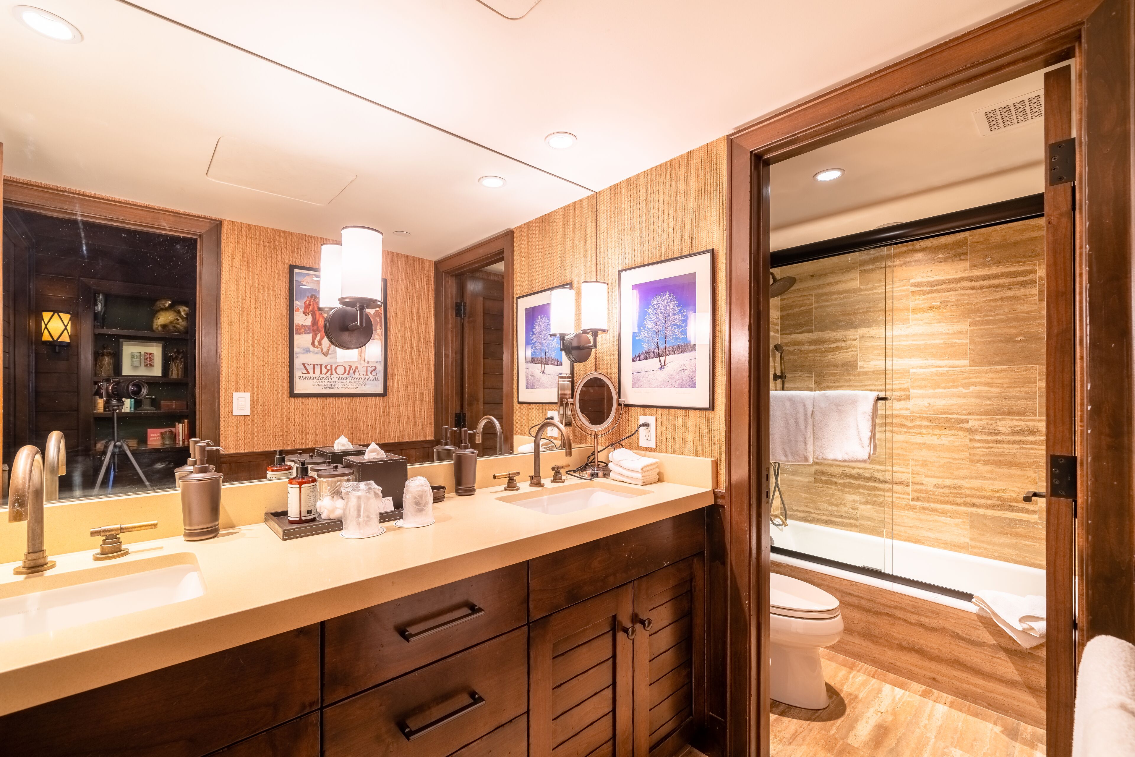 A modern bathroom with a wooden vanity, a large mirror, and a glass-enclosed shower area.