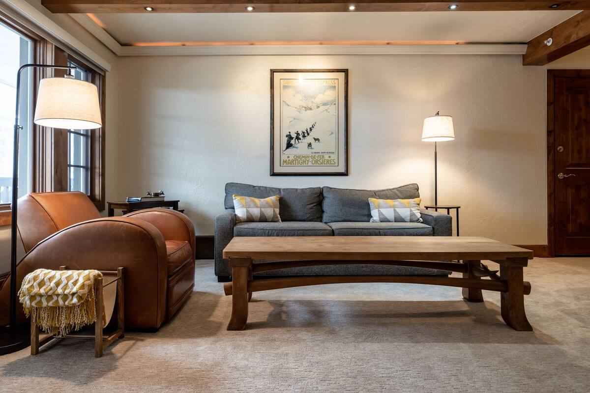 A cozy living room with a leather sofa, a wooden coffee table, and a framed poster on the wall.