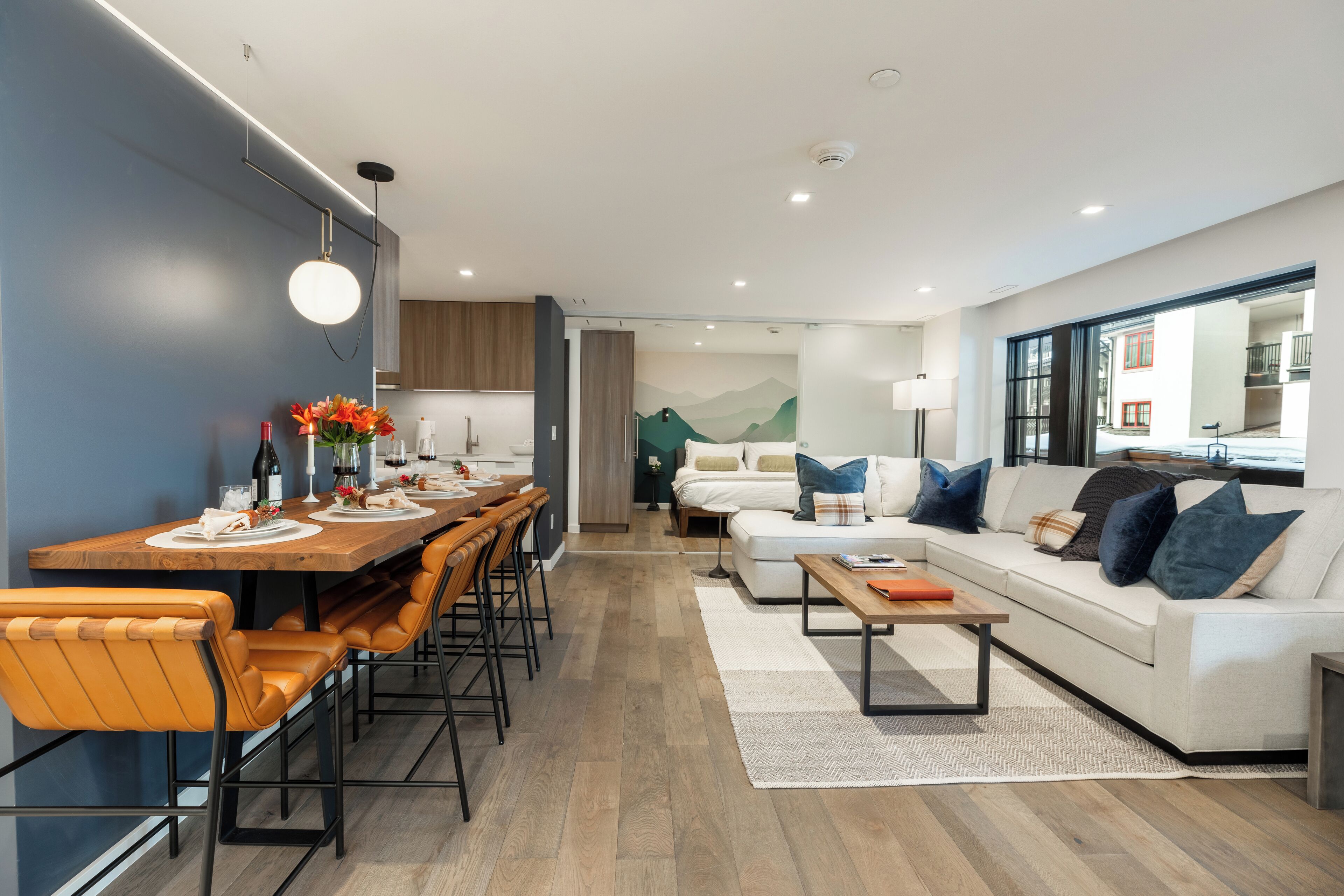A modern living room with a sofa, coffee table, and dining area with chairs and a table set for a meal.