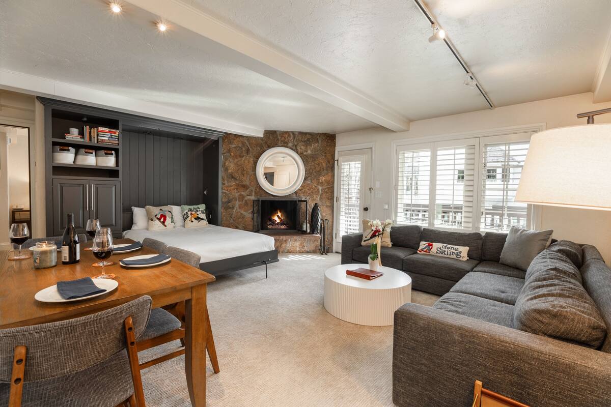A modern living room with a fireplace, a dining area, and a sofa.