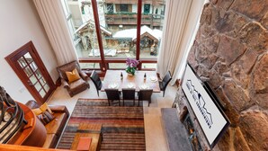 Un comedor con chimenea de piedra, un ventanal con vistas a un patio y una vista de un edificio con balcones.
