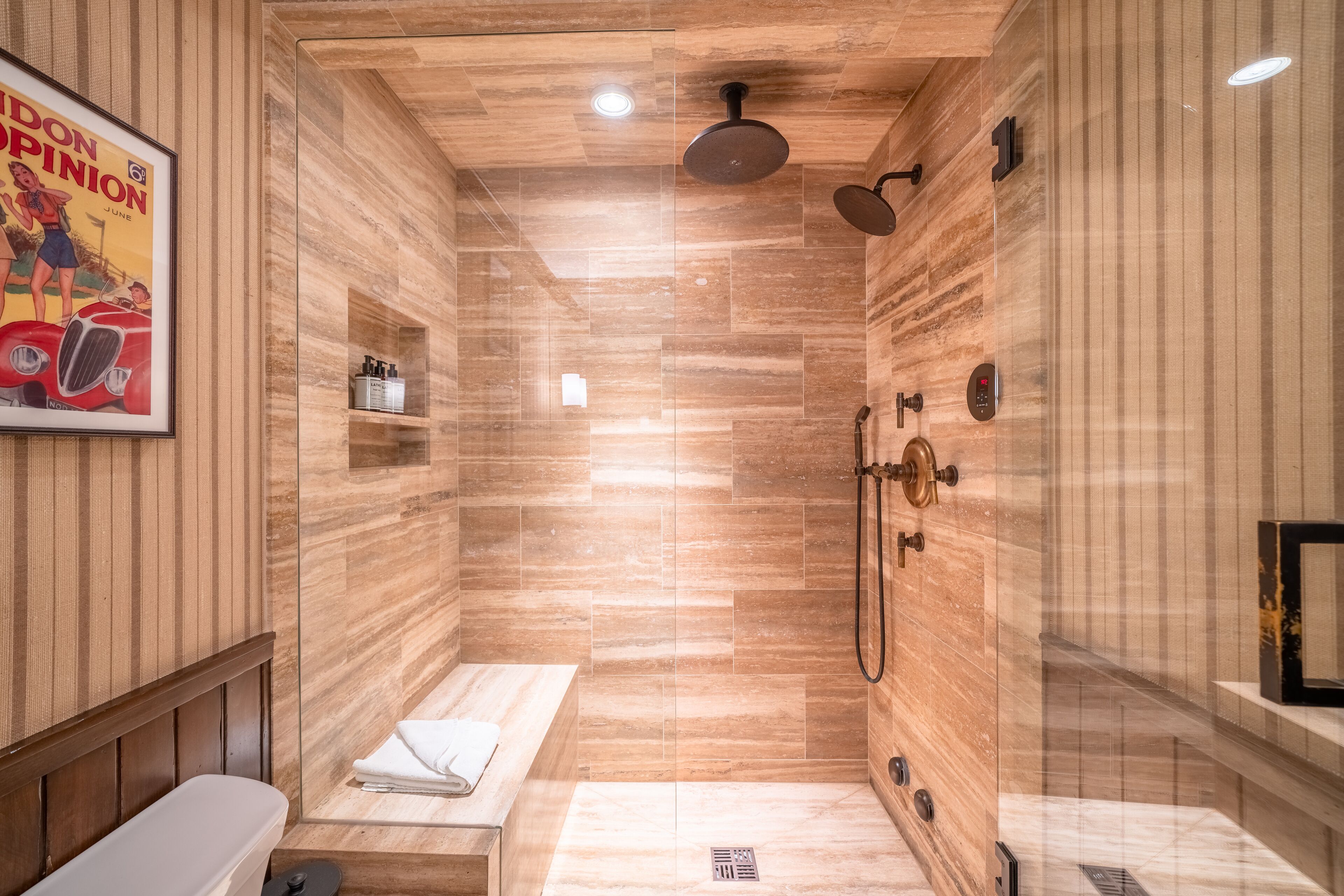 A modern shower area with a wooden panel design, a bench, and a mounted picture.