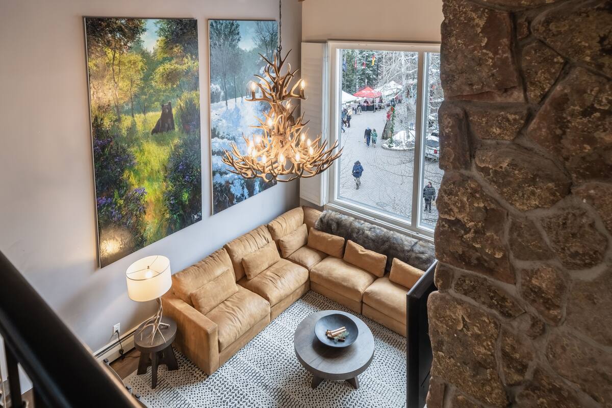 A cozy living room with a large sectional sofa, a round coffee table, and a unique chandelier.