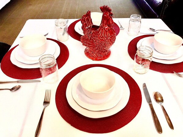 Una mesa con platos blancos, individuales con borde rojo y cubiertos.