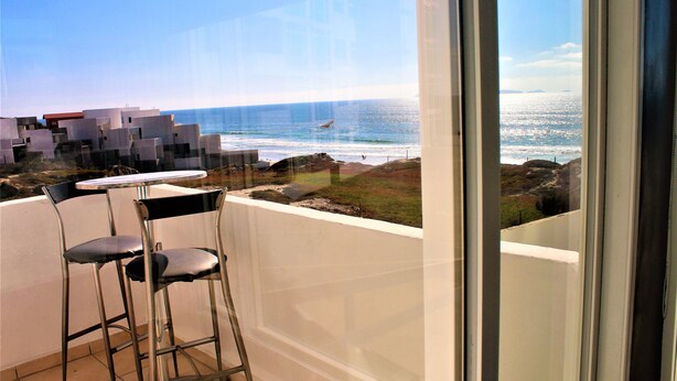 Un balcon avec vue sur l’océan, une chaise et une table.