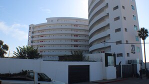 Un hôtel à plusieurs étages, doté d’une façade incurvée, de balcons et d’une entrée fermée par un portail.