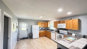A modern kitchen with wooden cabinets, a white refrigerator, a microwave, and a stove. - Perfect slice of peace and quiet by<br> (Lake Placid)
