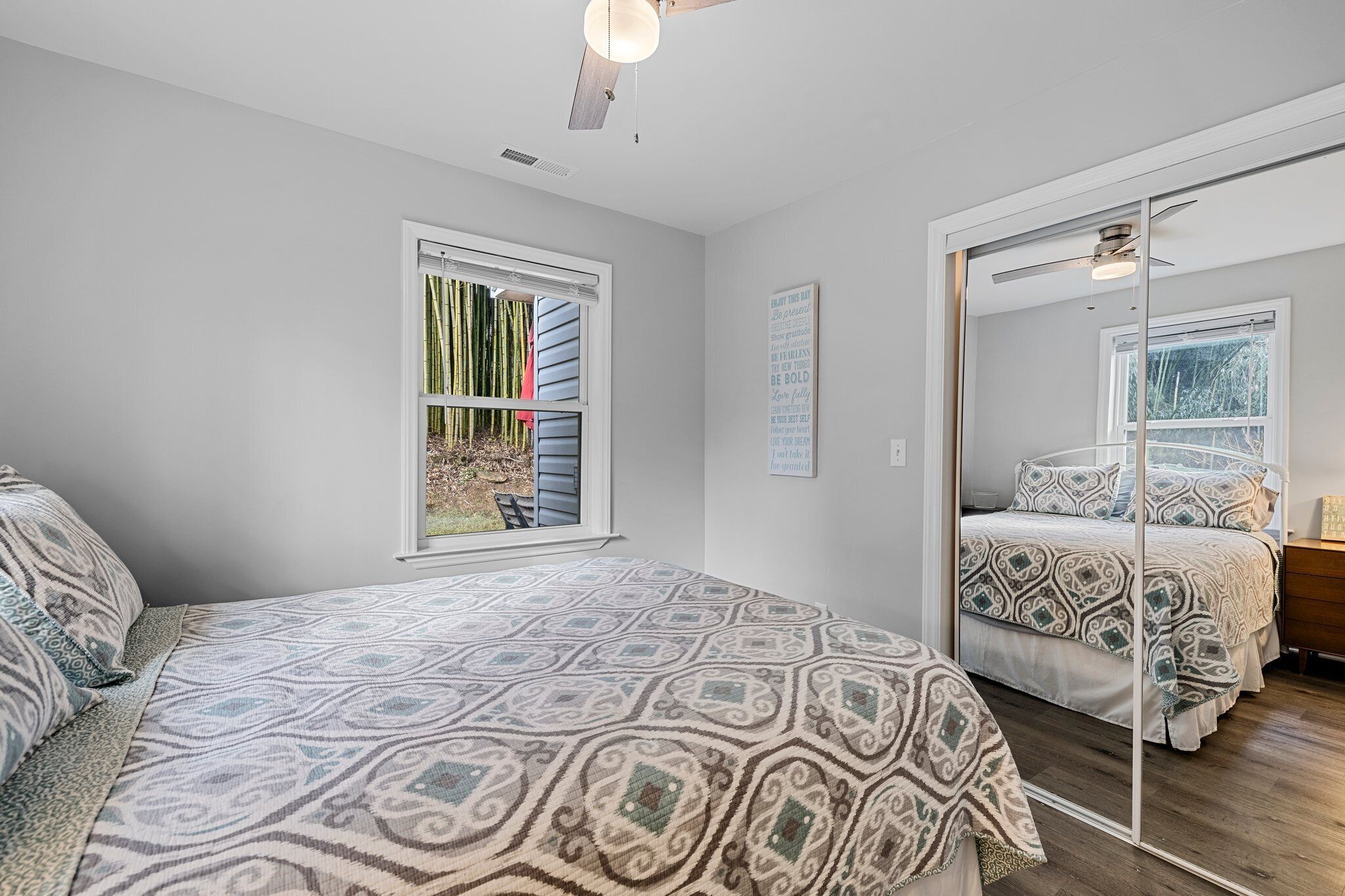 Un dormitorio con cama, ventana y espejo.