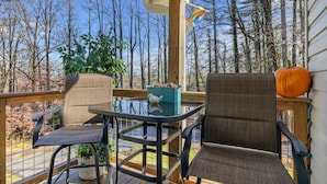 A wooden deck with two chairs and a table, surrounded by trees and a clear sky. - 1/4 Mile to Ecusta Trail • Firepit • 1G Fiber Wi-Fi • Bamboo Bungalow (Hendersonville)
