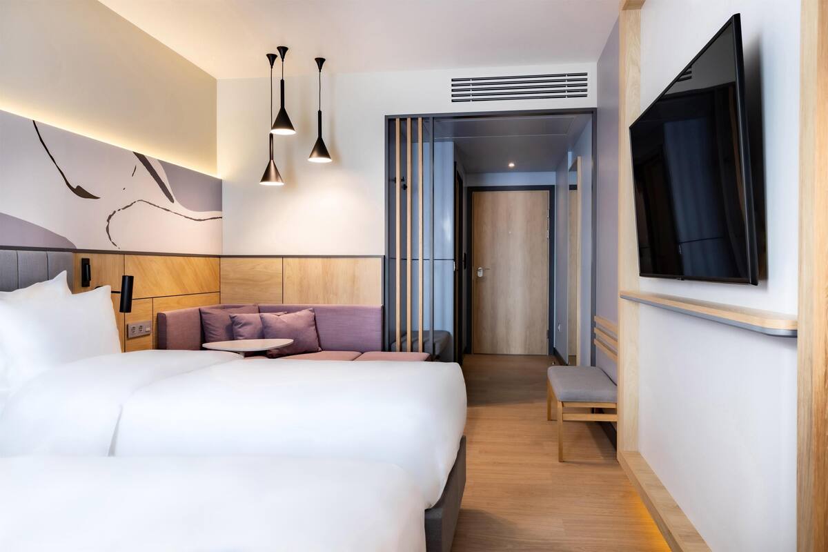 Une chambre d’hôtel moderne dotée d’un grand lit, d’un coin salon, d’une télévision et d’un mur décoratif en bois.